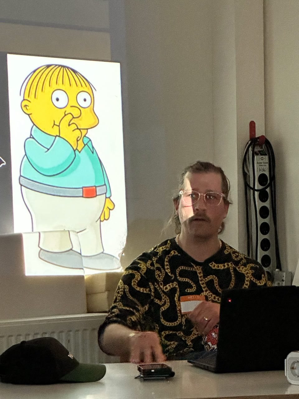 Tim Neunzig während des Vortrags, im Hintergrund eine Ralph-Wiggum-Folie.